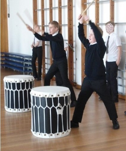 students using drum sticks to bang the drum